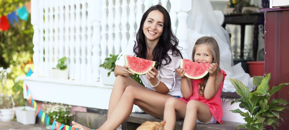 mom and daughter outside eating watermelon