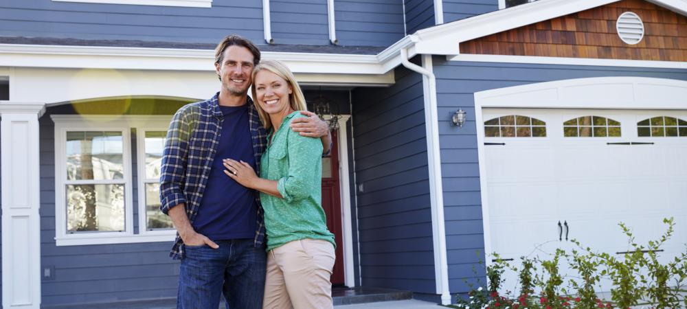 man and woman standing in front of a blue house